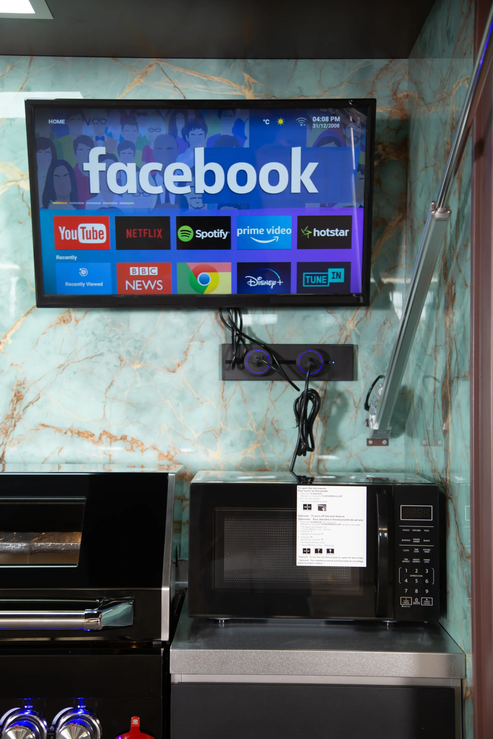 Microwave and television installed inside a sheltered outdoor kitchen appliance area