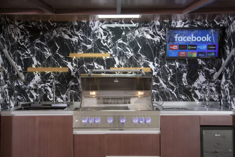 Built-in stainless steel grill and prep counters inside a motorized outdoor kitchen