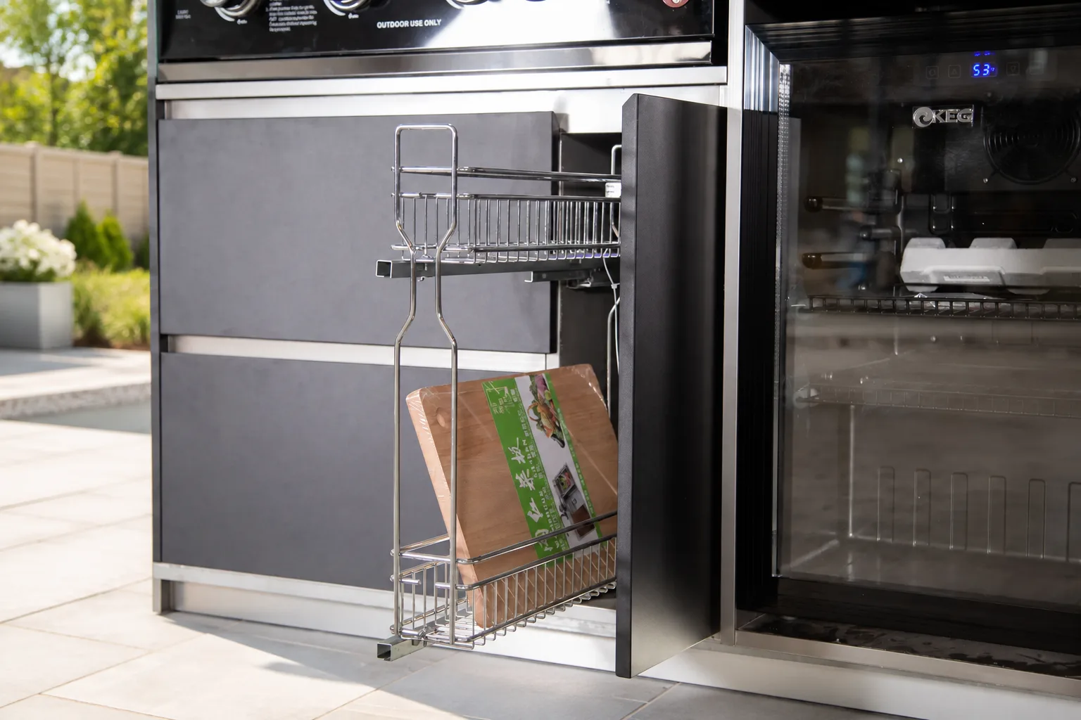 Outdoor kitchen pull-out storage in a bright family backyard patio