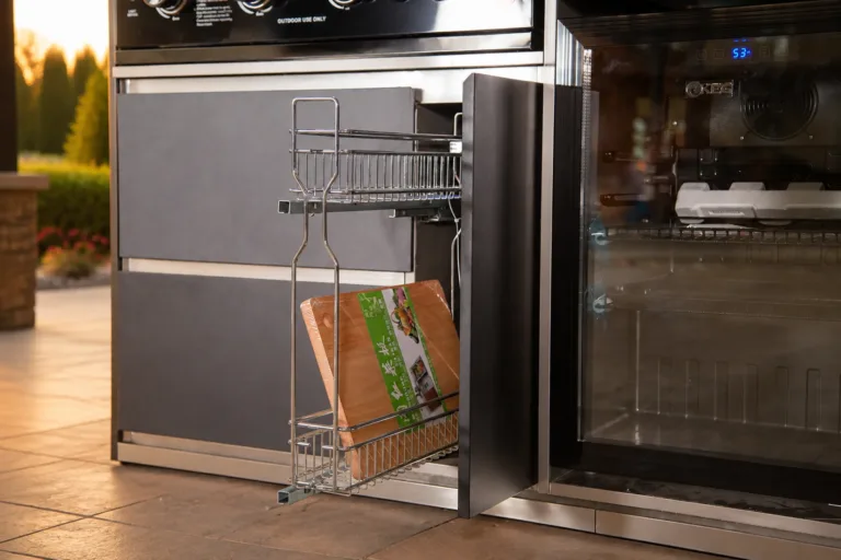 Luxury outdoor kitchen pull-out basket beside an integrated refrigerator at sunset